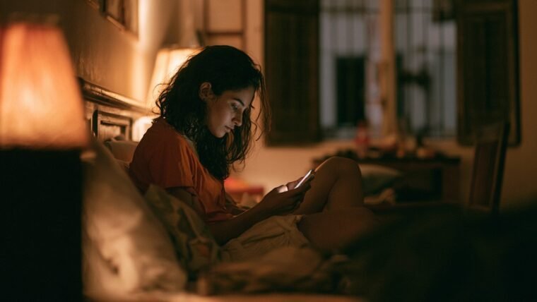 Woman sitting alone at night looking at a phone showing many missed calls