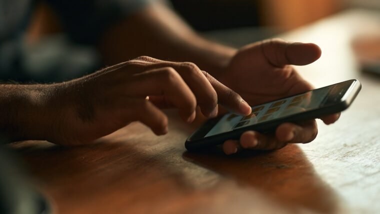 Close up of Indian hands tapping through folders on a smartphone screen to restore deleted files