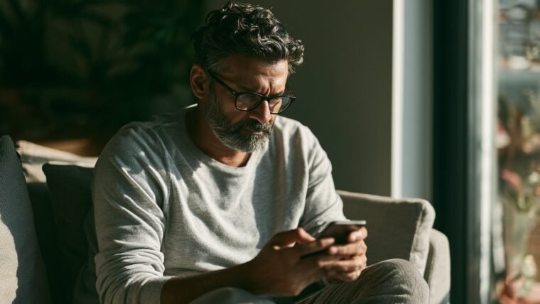 Worried Indian man at home looking at a suspicious message on his smartphone